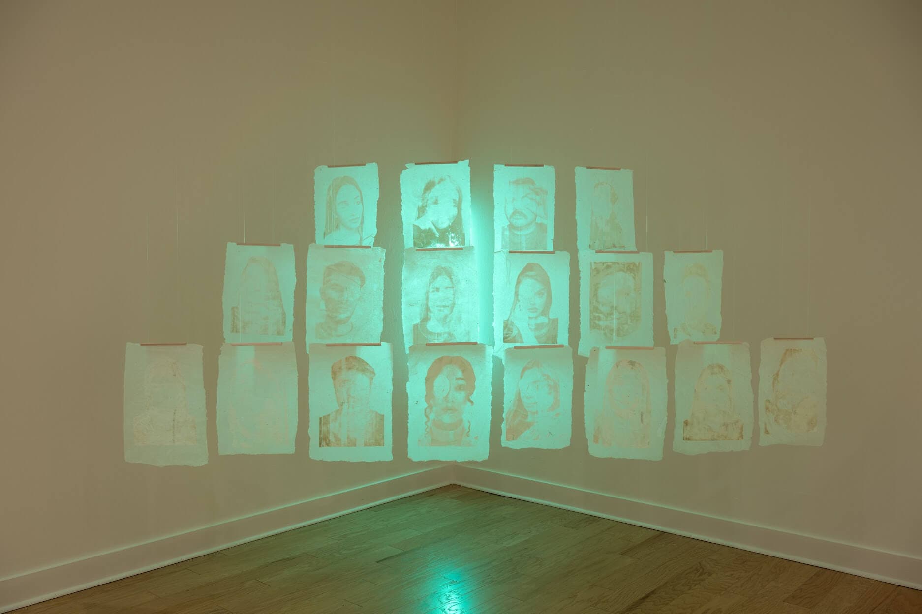 A squat pyramid of prints faintly etched with faces, lit up by a green light coming from beneath.